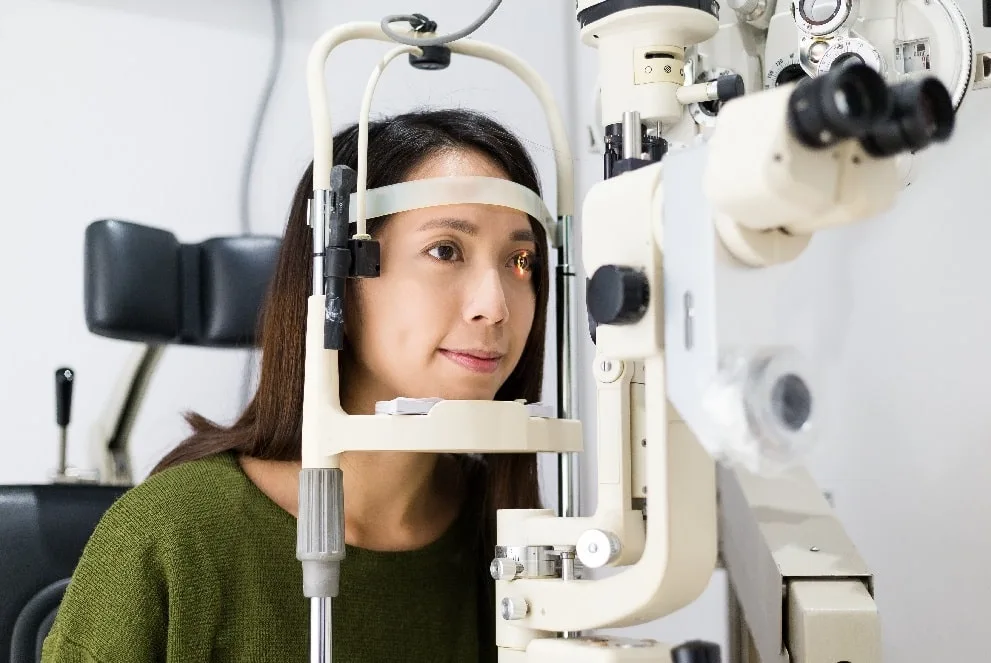 Woman undergoing an eye exam with a slit-lamp machine.